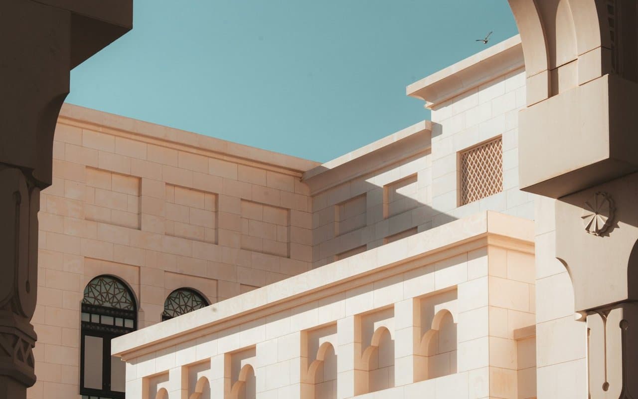 Arched sandstone Dubai building facade against a clear blue sky